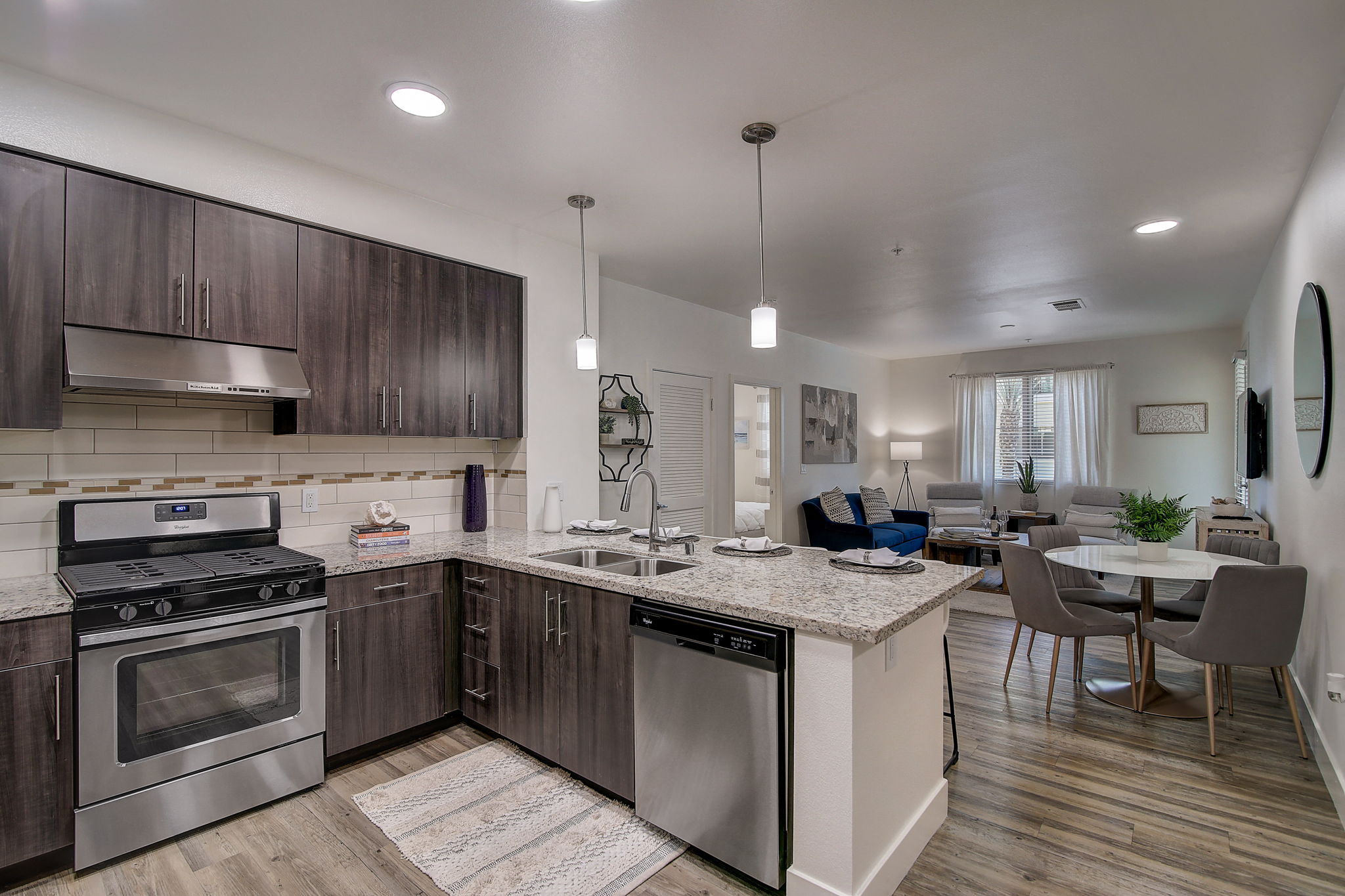 Modern open kitchen with stainless steel appliances, a marble countertop, and sleek cabinetry.